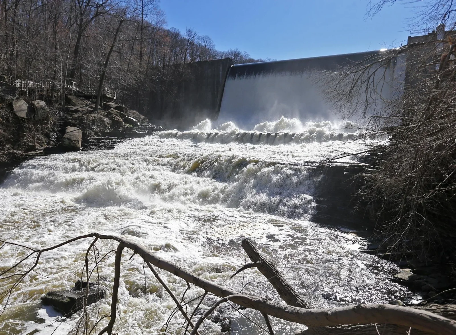 Water flows over a dam and through a rocky gorge.