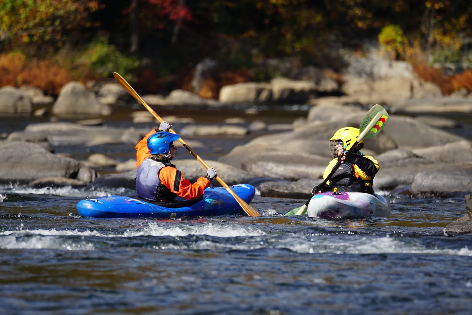 Two kayakers face each other on the river.